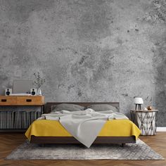 a bedroom with concrete walls and wooden flooring, yellow bedding and white sheets