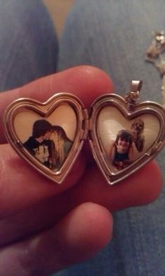 two heart shaped lockes with pictures in them are being held by someone's hand