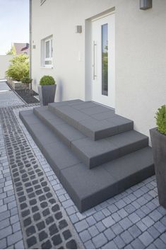 the steps are made of concrete and have planters on each side, along with potted plants