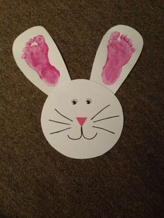 a paper cut out of a bunny's face with pink footprints on the ground