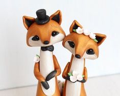 two small figurines in the shape of foxes wearing tuxedo hats and bow ties