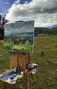 an artist's easel sitting on top of a grass covered field