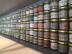 a wall full of jars filled with different types of spices and seasonings on display