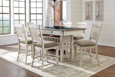 a dining room table with four chairs and a rug on the floor in front of it