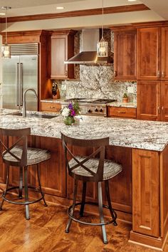 a kitchen with two bar stools next to an island in the middle of it