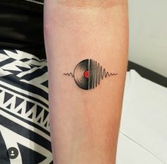 a woman's arm with a tattoo on it and a vinyl record in the middle