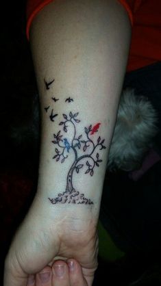 a person with a tattoo on their arm holding a small tree and birds in the air