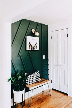 a room with a bench, plant and pictures on the wall