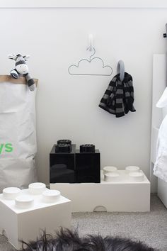 a dog laying on the floor in front of a white wall with toys hanging from it's hooks