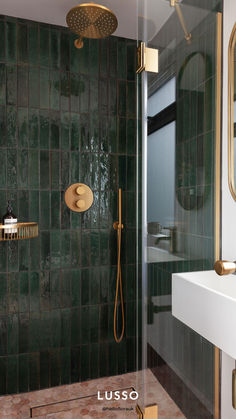 a green tiled bathroom with gold fixtures and brass fixtures on the shower head, sink, and mirror