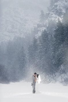 a bride and groom standing in the snow