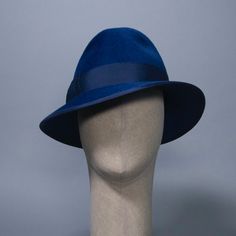 A timeless fedora inspired by the sultry style of Marlene Dietrich. In rich lapis blue velour felt with grosgrain band and bow. Materials: Ethically sourced fur felt, Grosgrain Ribbon, Millinery Wire Style: Fedora Measurements: Crown height 4.25 in (11 cm) Brim width at deepest over right eye 3.25 in (6 cm) Hat Box: 14 in How to Wear: Classic fit Ready to Ship in a size L (23 in / 58 cm). Other sizes will be Made to Order. Katrina is part of the A/W 2023 "Stardust and Stories" collection. Limite