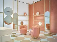 a room with pink chairs and mirrors on the walls, in front of a white floor