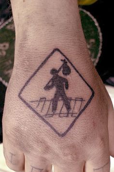 a person's hand with a tattoo on it that has a walk sign in the middle