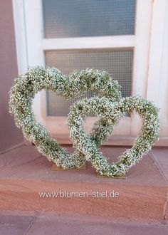 two heart shaped wreaths sitting in front of a window