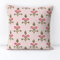 a pink and green floral pillow on a white surface with polka dotty dots in the background