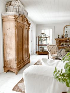 a living room filled with furniture and a tall wooden cabinet next to a mirror on the wall