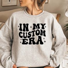 In My Era Custom Sweatshirt, Personalized Sweatshirt, Custom Era Hoodie, Concert Outfit, In My Era Sweater HOW TO ORDER 1. Check our photos for color and sizing options.  2. Choose your quantity. 3. Select your size and color from the drop-down menus. 4. Click "ADD TO CART" to add the shirt to your virtual cart.  5. Click "PROCEED TO CHECKOUT" to purchase your shirt.  6. Your shirt is now off to production! We will process your order and your shirt will be ready to ship in 1-3 days! PRODUCTION a Band Merch Long Sleeve Sweatshirt With Custom Print, Customizable Cotton Sweater For Winter, Customizable Winter Streetwear Tops, Customizable Winter Hoodie Tops, Hoodie Concert Outfit, In My Era, Custom Sweatshirts, Concert Outfit, Long Sweatshirt