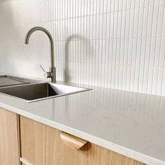 a kitchen sink sitting under a faucet next to a counter top with a wooden cabinet