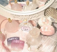 an assortment of perfume bottles sitting on top of a white table next to a mirror