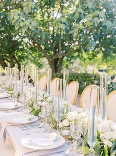 a long table is set with white flowers and place settings for an elegant dinner party