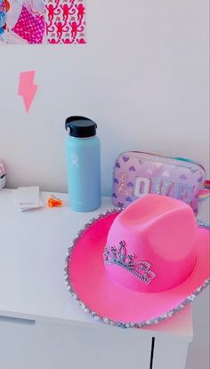 a pink cowboy hat sitting on top of a white table next to a blue cup