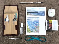 art supplies laid out on the ground with watercolors