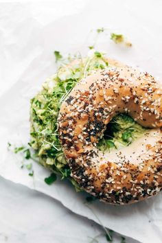 a bagel covered in sesame seeds and sprouts on top of a white napkin