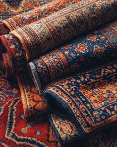 several rugs are stacked on top of each other in different colors and patterns,