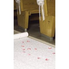 rose petals are on the floor in front of a wooden church pew with ribbons tied to it