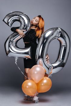 an image of a woman holding balloons and the number twenty eight in front of her