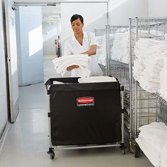 a woman ironing clothes in a large room with shelving and shelves full of white sheets