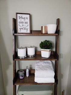 a bathroom shelf with towels, candles and other items on it in front of a toilet