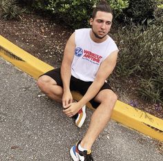 a man sitting on the side of a road next to bushes