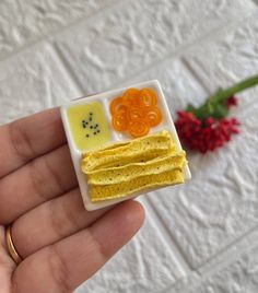 a tiny plate with food on it in someone's hand next to a flower