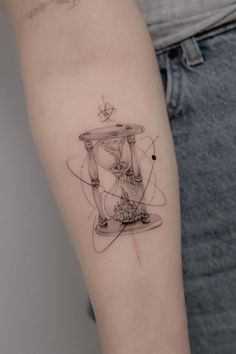 a woman's arm with a tattoo on it that has an hourglass in the middle