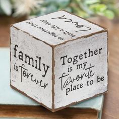 a wooden block that says family is forever and has writing on the side, sitting on top of a book