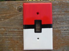 a red and white light switch sitting on top of a wooden fence