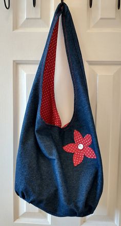 a blue purse hanging from a hook on a white door with polka dots and red flower applique