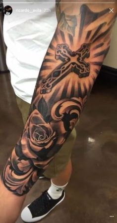 a man with a cross and roses tattoo on his arm