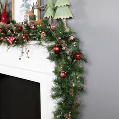 a mantel decorated with christmas decorations and greenery