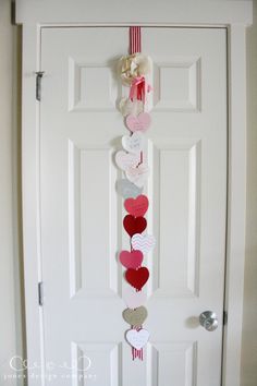 a valentine's day decoration hanging on the front door with hearts attached to it