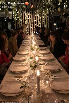 the long table is set with white plates and place settings for dinner guests to enjoy