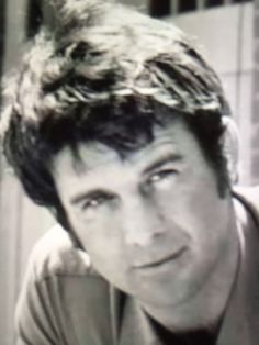 black and white photo of man with messy hair looking to the side in front of window