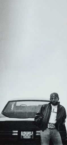 a black and white photo of a man standing next to a car