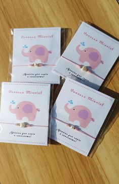 three pink elephant themed business cards sitting on top of a wooden table