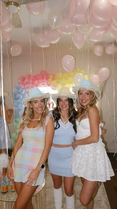 three beautiful women standing next to each other in front of balloons and confetti