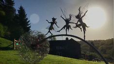 three metal statues on top of a green hill