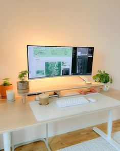 a white desk with a computer monitor and keyboard on it, along with potted plants