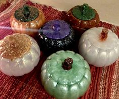 five different colored glass pumpkins sitting on a table top with glittery tops and lids